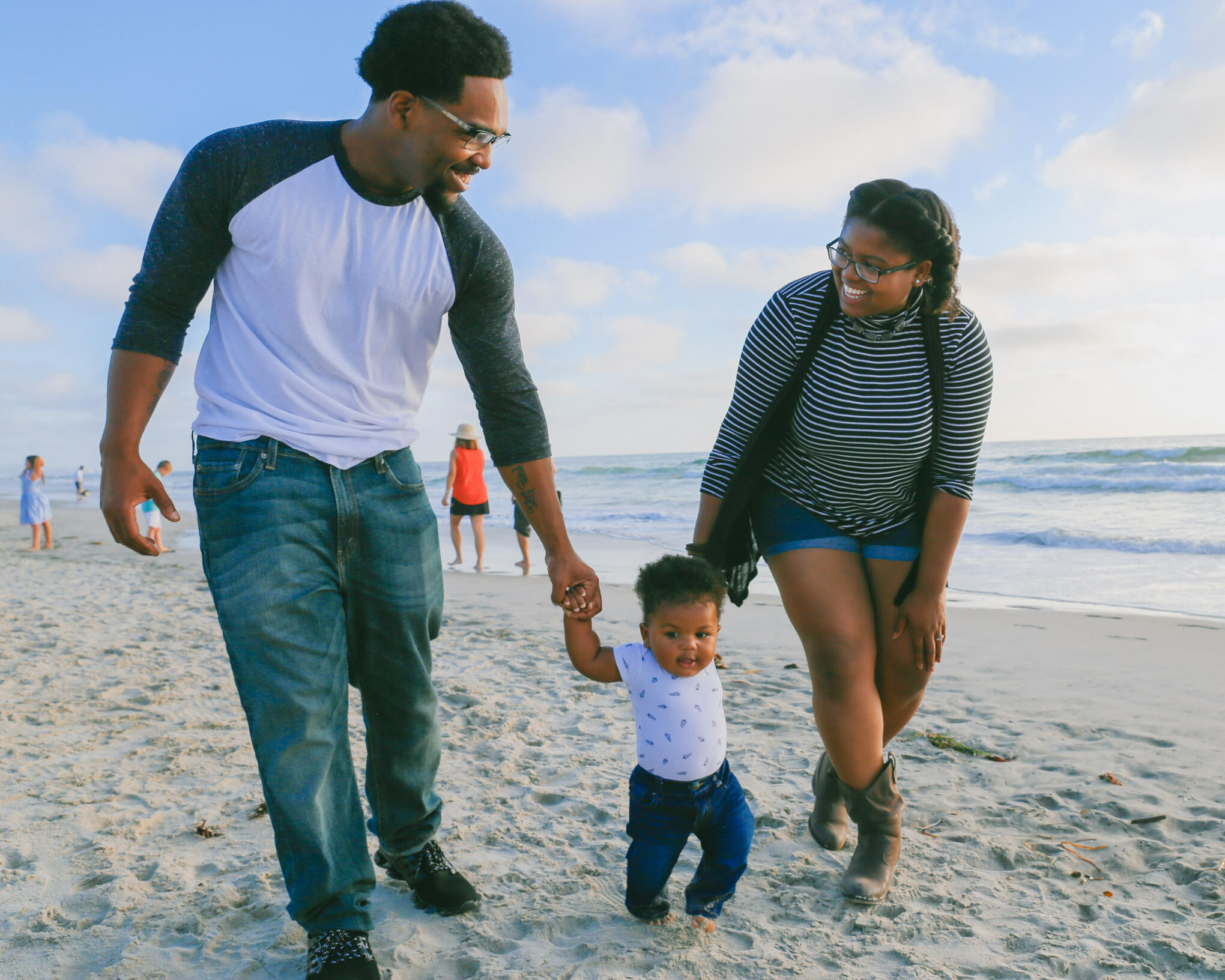 Happy couple walking with their child down the beach